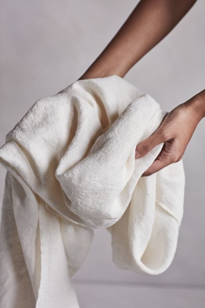 Hands holding a soft upcycled textile sheet.